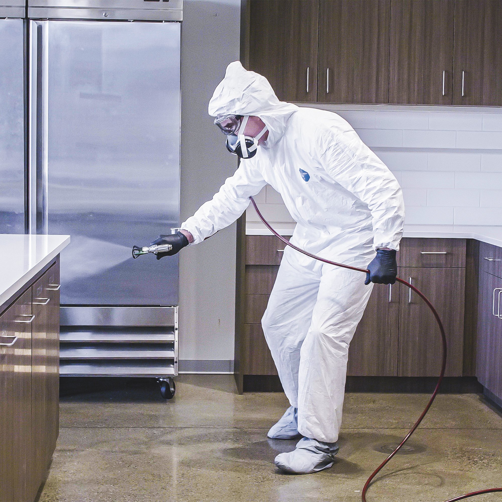 Person using disinfectant sprayer in kitchen